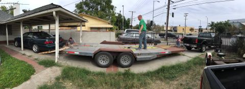 1993 Ford Taurus - A dark sedan is being loaded onto a trailer, with a black pickup truck visible in the background.