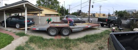 1993 Ford Taurus - A dark 1993 Ford Taurus is being loaded onto a car trailer in a driveway.