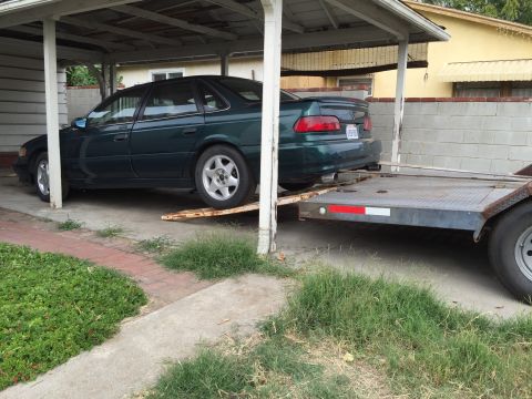 1993 Ford Taurus - Green 1993 Ford Taurus being loaded onto a trailer under a carport.