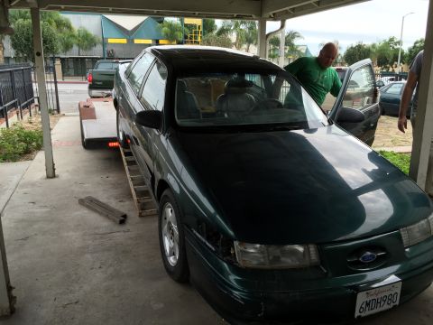 1993 Ford Taurus - 1993 Ford Taurus being loaded onto a trailer, with a man assisting.