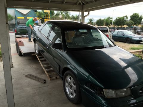 1993 Ford Taurus - A 1993 Ford Taurus is being loaded onto a trailer, with another vehicle visible in the background.