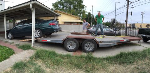 1993 Ford Taurus - A green sedan is being loaded onto a car trailer by two men, with another vehicle visible in the background.