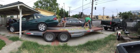1993 Ford Taurus - A green 1994 Ford Taurus sedan is loaded onto a car trailer, with a black pickup truck visible in the background.