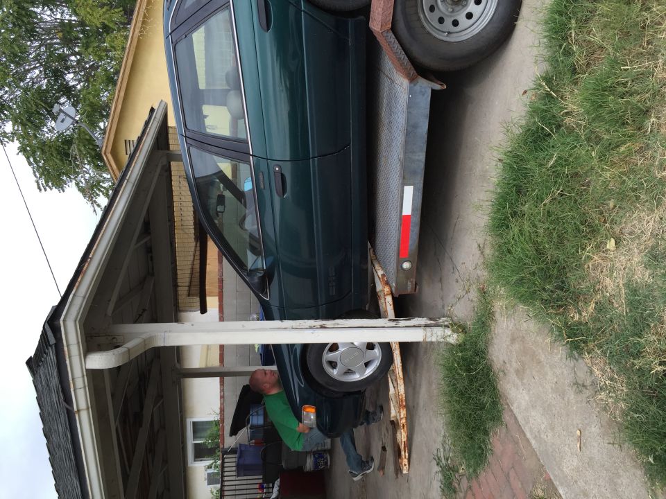 Green 1993 Ford Taurus sedan on a trailer, side view