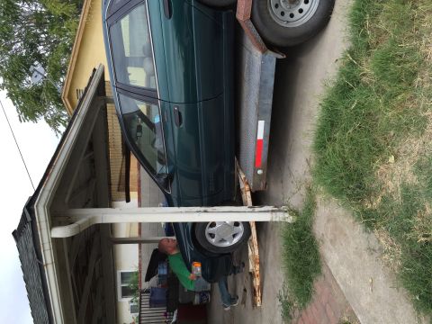 1993 Ford Taurus - Green 1993 Ford Taurus loaded onto a trailer, with a person assisting.