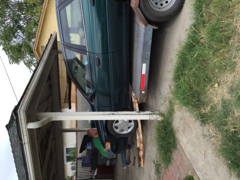 1993 Ford Taurus - A green sedan is being loaded onto a trailer under a carport.