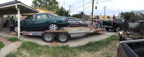 1993 Ford Taurus - A green 1993 Ford Taurus is being loaded onto a trailer, with a black pickup truck visible in the background.