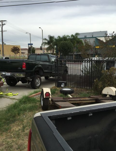 1993 Ford Taurus - A dark green pickup truck is parked next to a trailer, with another truck's bed visible in the foreground.