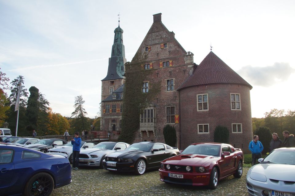 Red Ford Mustang with license plate 08-HL-69 parked in front of a castle