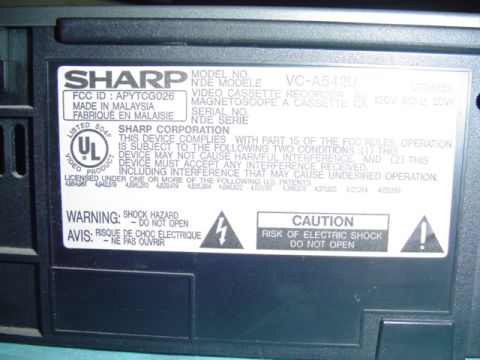 1999 Ford Taurus - This label details the model number, FCC ID, and safety warnings for a SHARP VC-A542U VCR.
