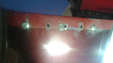 1996 Ford Bronco - Close-up of a red tailgate showing holes drilled for repair work.