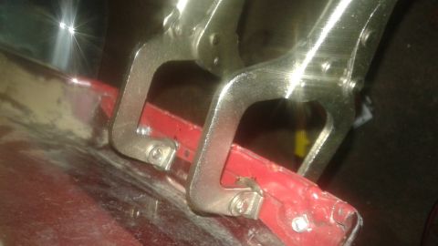 1996 Ford Bronco - Locking pliers are clamped onto a red metal component, likely during a repair or fabrication process.