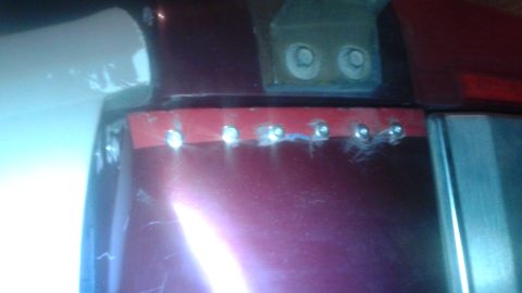 1996 Ford Bronco - Close-up of a maroon tailgate showing evidence of repair work, including rivets and red tape.