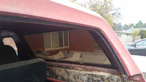 1981 Ford Bronco - The interior of a red vehicle shows a small boat parked in the driveway outside.