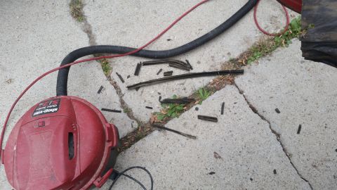 1981 Ford Bronco - Debris from removed weatherstripping lies on the ground next to a Shop-Vac and its hose.