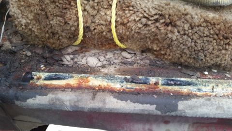 1981 Ford Bronco - Close-up of rusted metal and carpet padding, possibly from a vehicle interior.
