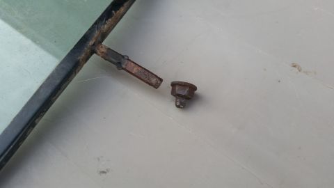 1981 Ford Bronco - Close-up of a rusted metal window frame and a loose bolt, likely from a vehicle part.