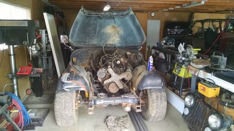 1985 Jeep CJ7 - A Jeep CJ is in a garage with its hood and engine exposed, with another Jeep visible in the background.