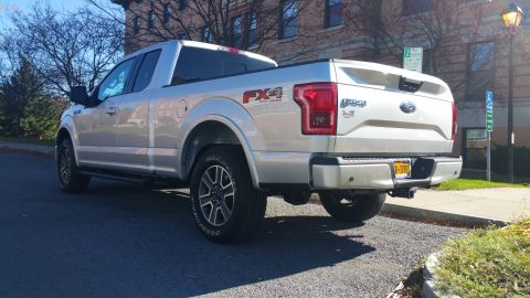 2015 Ford F-150 - A silver Ford F-150 pickup truck is parked on a street with a building in the background.