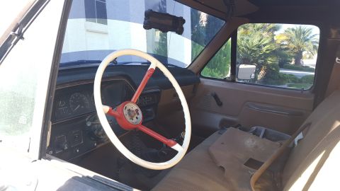 1988 Ford Bronco - The interior of a 1988 Ford Bronco, a distinctive red and white steering wheel and tan upholstery.