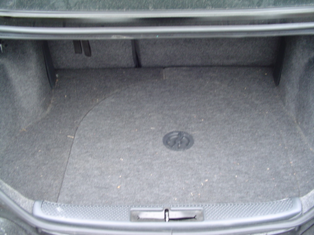 Empty car trunk with gray carpet and a circular emblem in the center