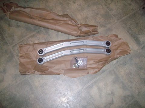2004 Ford Crown Victoria - Aftermarket rear control arms and hardware are laid out on brown paper, likely for installation.