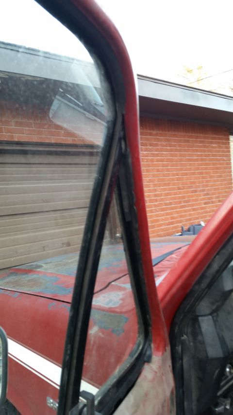 1981 Ford Bronco - Close-up of the door frame and weatherstripping on a red 1981 Ford Bronco, showing signs of wear and tear.