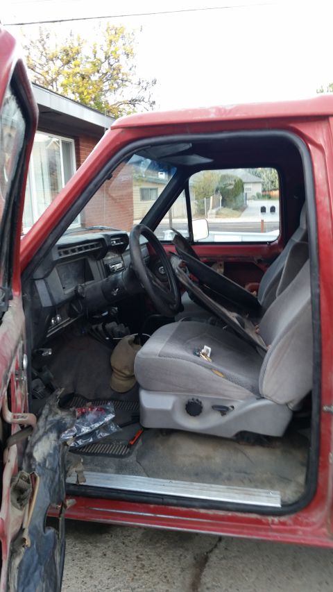 1981 Ford Bronco - Interior view of a red truck, showing the driver's seat, dashboard, and open door.