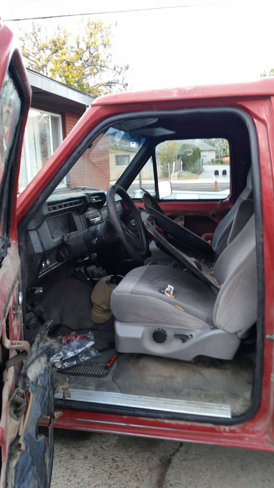 Red truck interior with worn seats and dashboard. Open driver's door