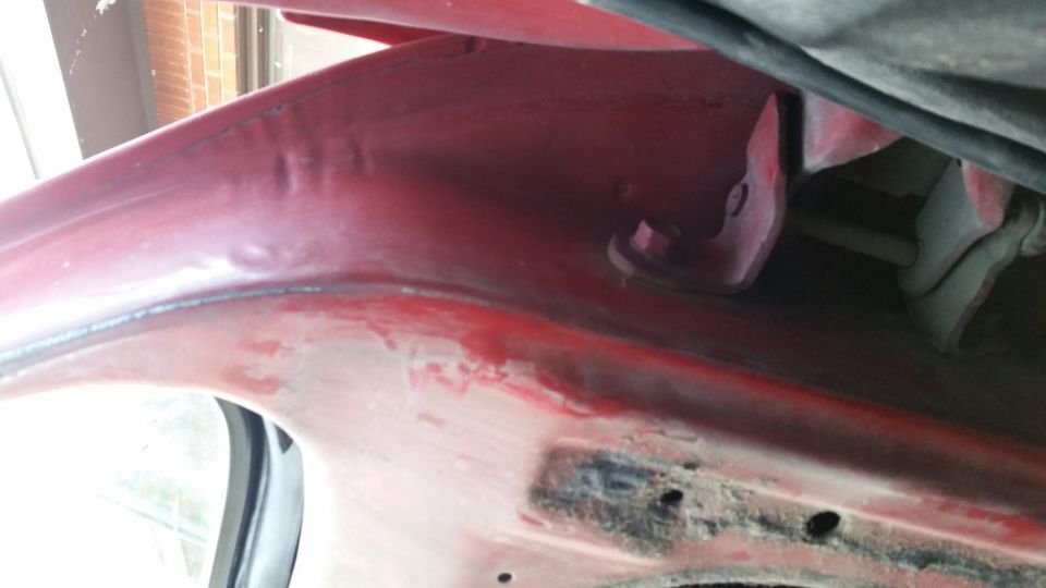 red painted interior of a vehicle's wheel well with some rust and a black cable