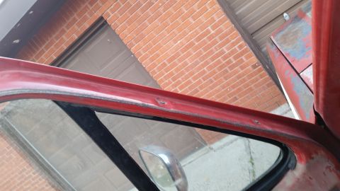 1981 Ford Bronco - Close-up of a vehicle's red door frame, showing the condition of the weatherstripping and surrounding metal.
