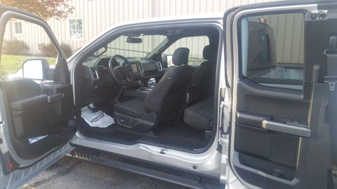 2015 Ford F-150 - The interior of a silver 2015 Ford F-150 pickup truck is visible with the passenger doors open.