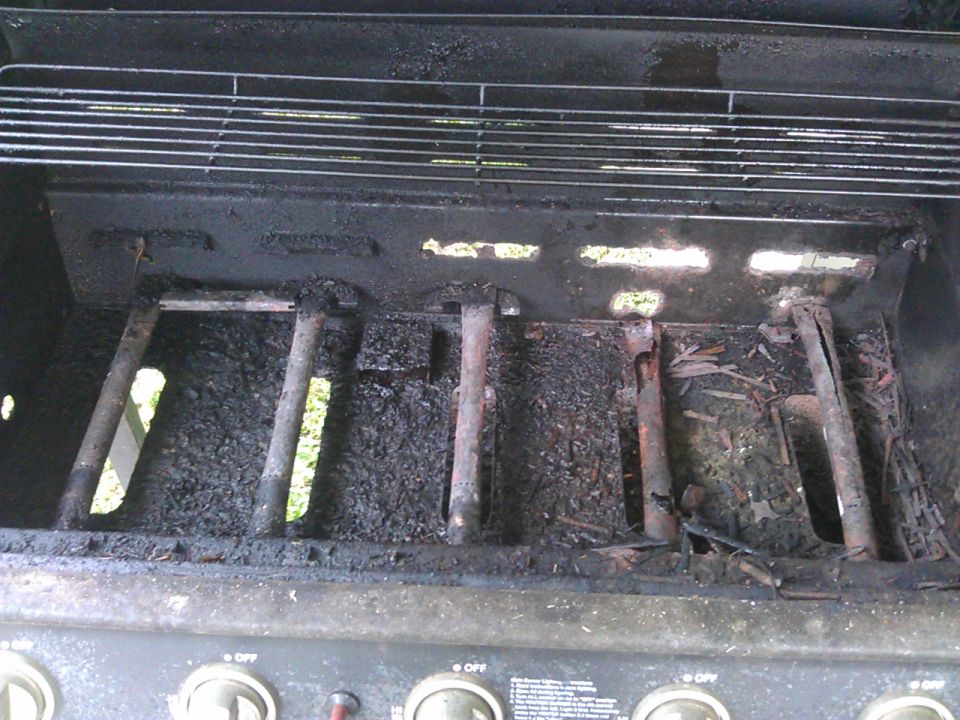 Dirty grill burners and grates with ash and debris