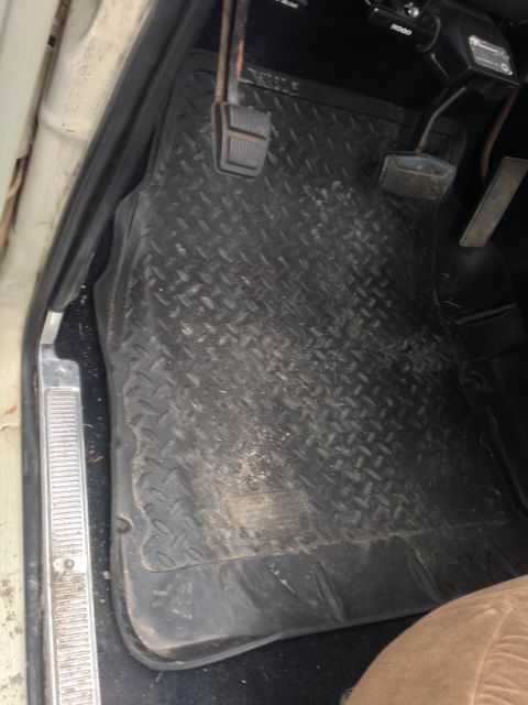 1979 Ford Bronco - The driver's side floor of a vehicle is covered with black diamond plate mats and shows the brake and accelerator pedals.