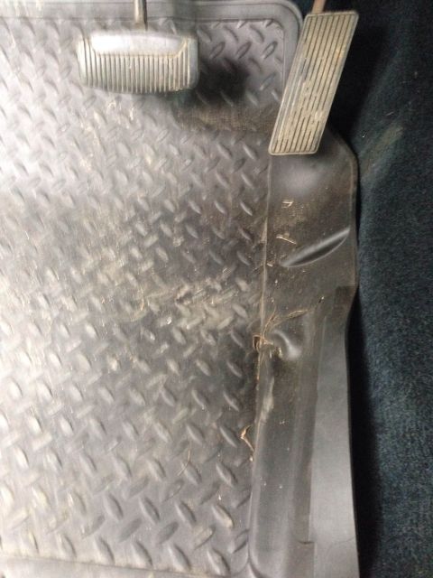 1979 Ford Bronco - Close-up of the floor and pedals inside a vehicle, showing a diamond plate mat and dark carpeting.