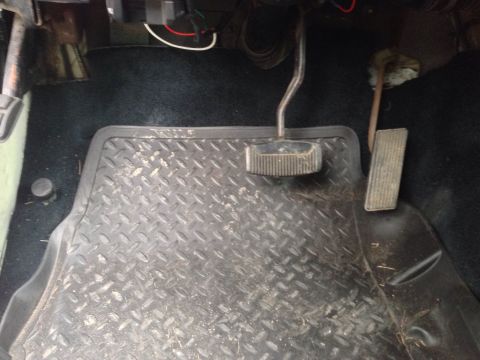 1979 Ford Bronco - The interior floor of a vehicle shows diamond plate floor mats and the brake and gas pedals.