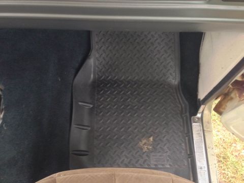 1979 Ford Bronco - The interior of a vehicle shows a black diamond plate floor mat covering the carpeted floor.