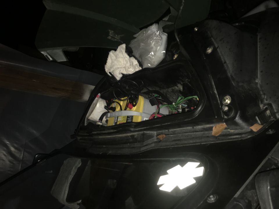 Interior compartment with yellow battery, wires, and some debris