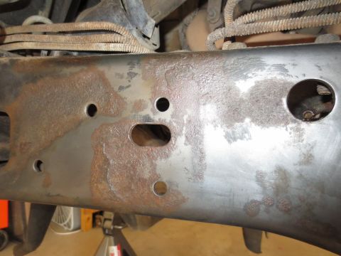 1996 Ford Bronco - Close-up view of a heavily rusted frame rail, showing various holes and electrical wiring above.