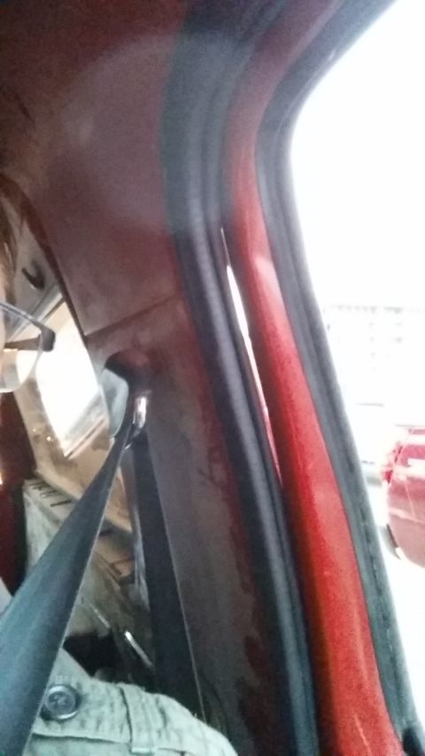 1981 Ford Bronco - Close-up view of the interior door frame and weatherstripping on a red vehicle, with another vehicle visible outside.
