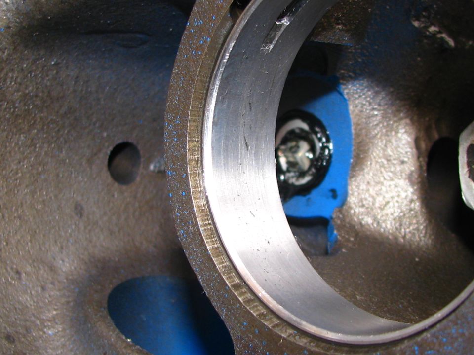 Close-up of an engine's bearing housing with blue paint and a bolt visible