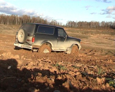1987 Ford Bronco - This 1987 Ford Bronco is stuck deep in the mud, with trees in the background.
