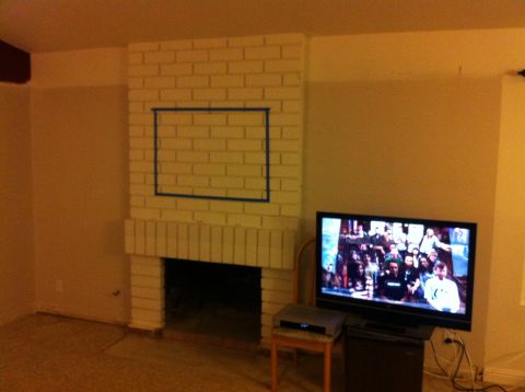 1990 Ford Probe - A living room scene a brick fireplace and a television displaying a group of people.