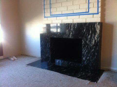 1990 Ford Probe - A fireplace with a black marble surround is shown, with blue tape marking off the white brick above.