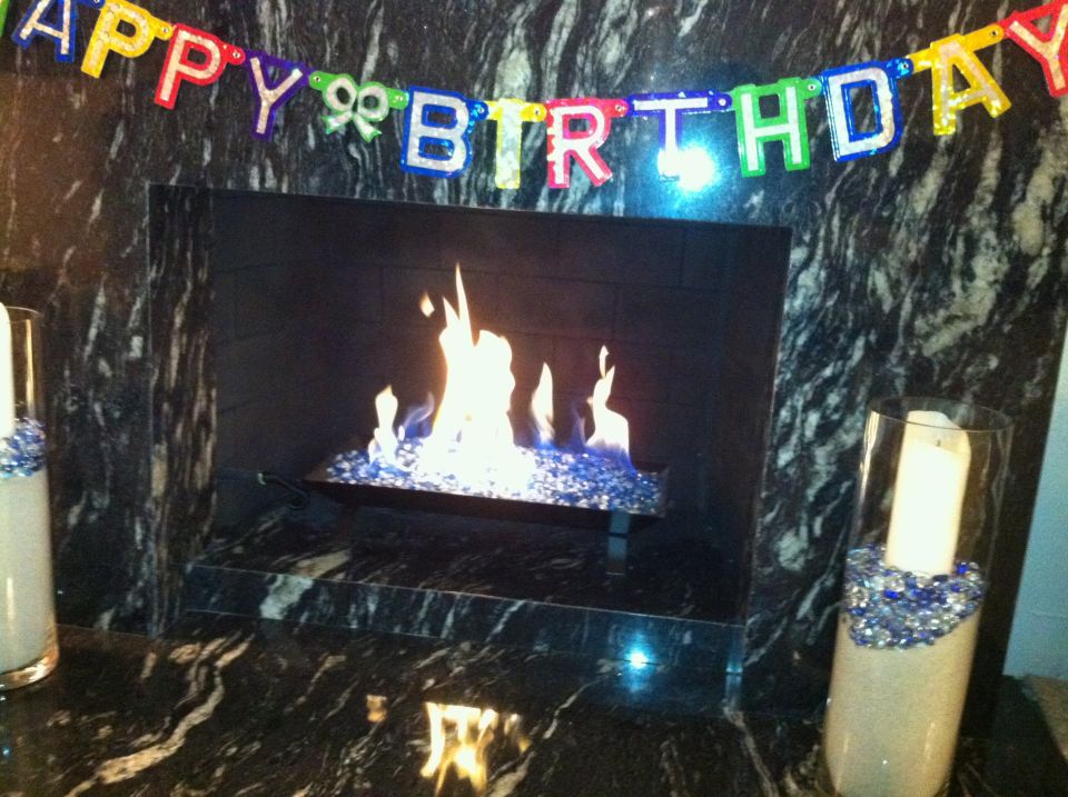 Birthday banner above a lit fireplace with decorative vases on either side