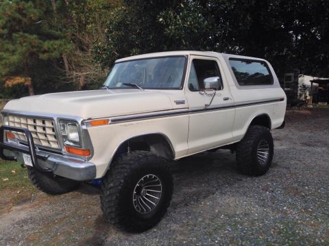 1979 Ford Bronco - This lifted 1979 Ford Bronco sits on a gravel lot with trees in the background.