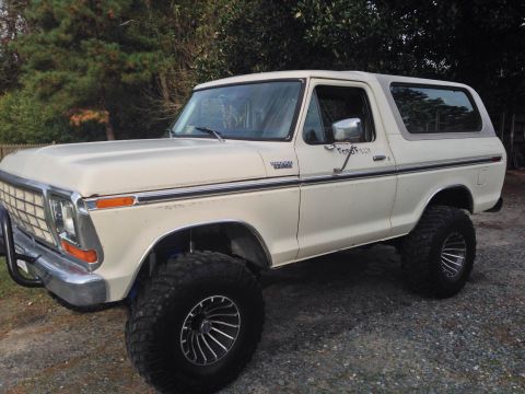 1979 Ford Bronco - This lifted Ford Bronco sits on a gravel surface with trees in the background.