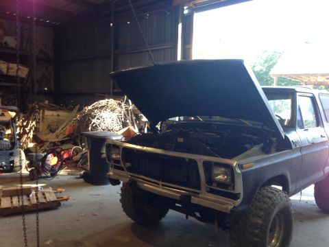 1979 Ford Bronco - Ford Bronco with hood up in a cluttered garage, showing engine and suspension.