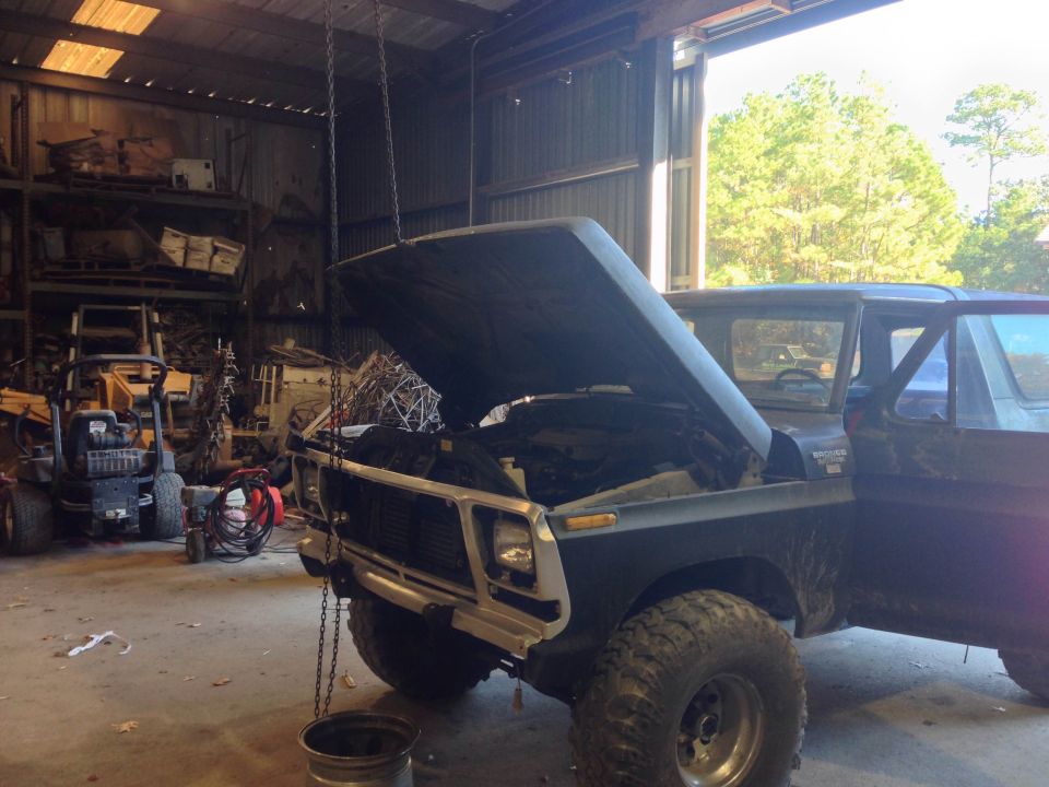 Dark blue 1978 Ford Bronco with hood open, parked in a garage with tools and equipment