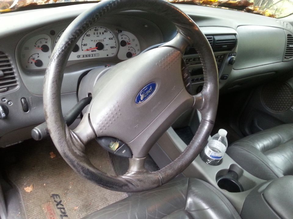 Interior shot of a 2001 Ford Explorer, showing the steering wheel, dashboard, and center console with a water bottle